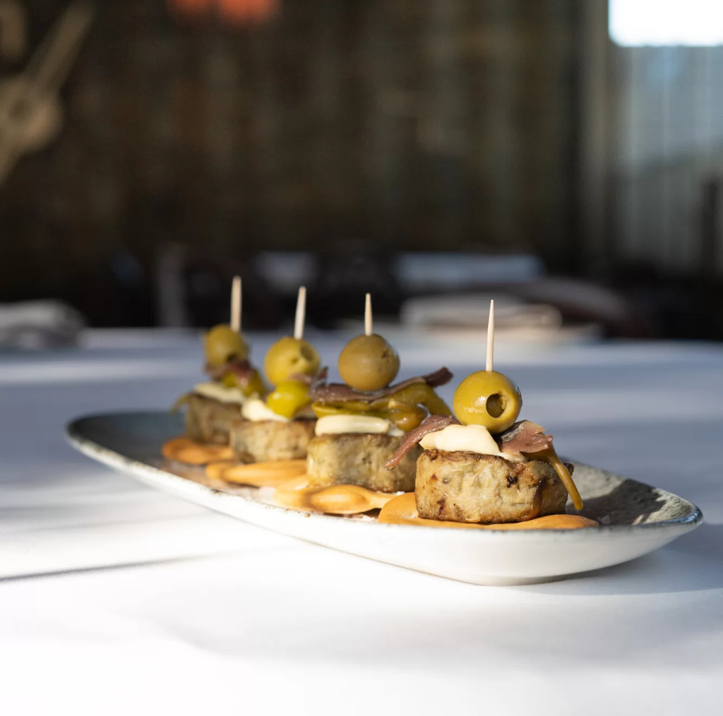 Platter of small mini artichoke burger appetizers with olives.